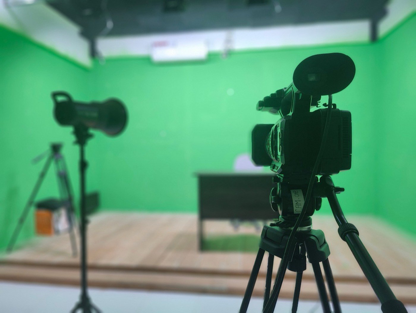 Camera on a tripod and a studio light in the WhiteFox green-screen studio