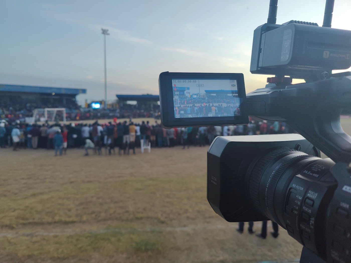A camera with wireless transmitter on the sideline of a packed football ground